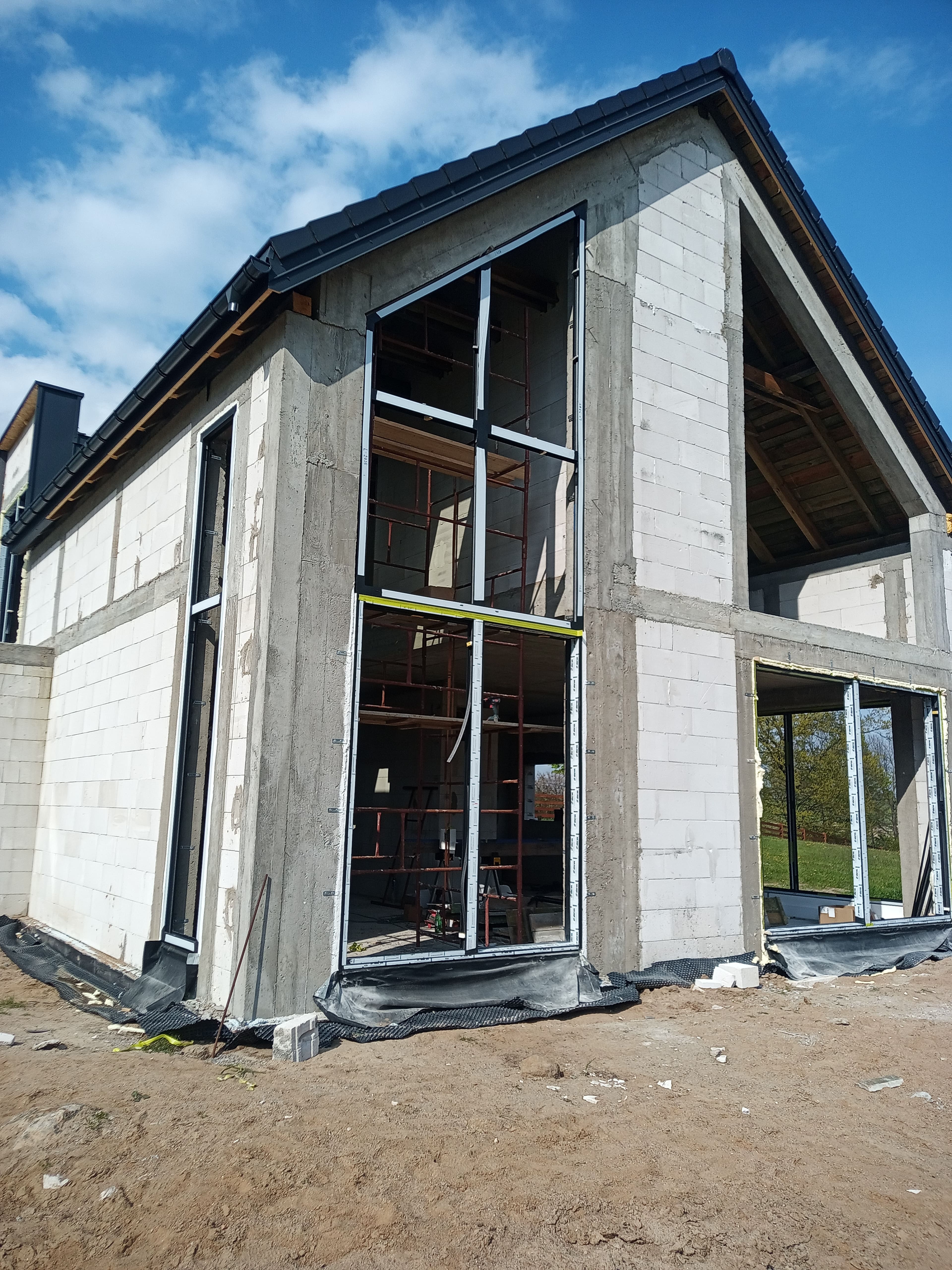 Aluminiowe: fasada dwukondygnacyjna, trójkątne okno panoramiczne oraz okno przesuwne typu HS w domu jednorodzinnym