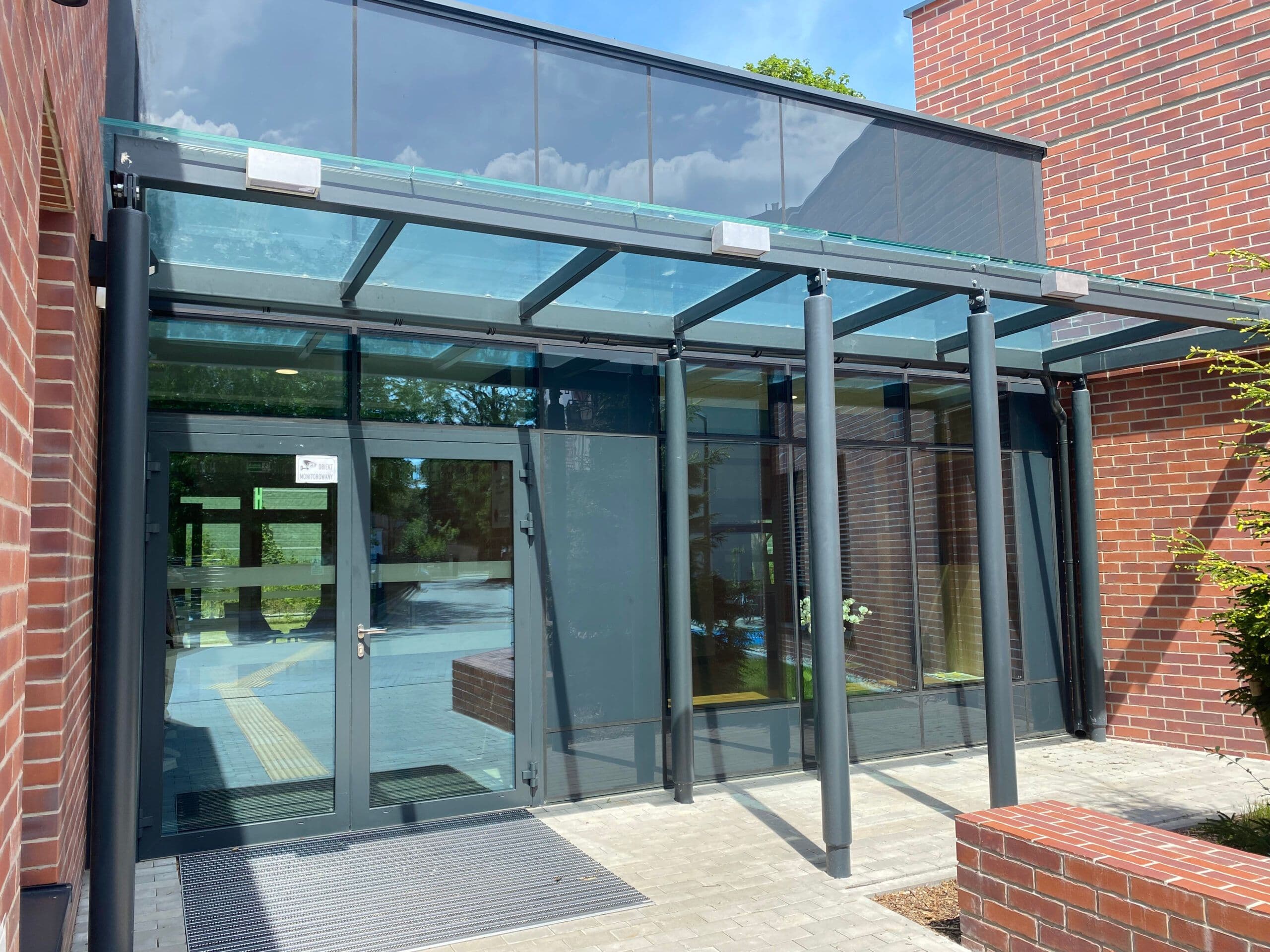 Szklany przedsionek z zadaszeniem na konstrukcji aluminiowej, drzwi aluminiowe