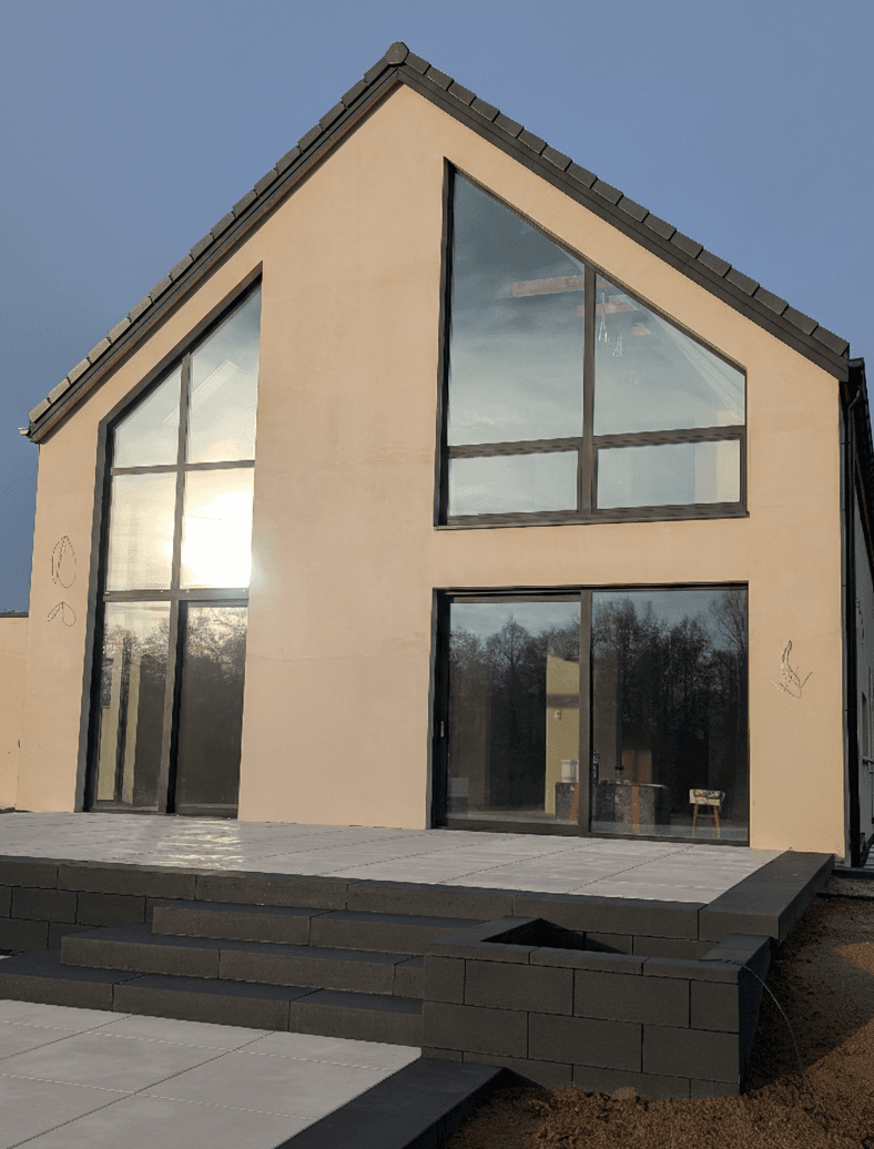 Aluminiowe: fasada dwukondygnacyjna, trójkątne okno panoramiczne oraz okno przesuwne typu HS w domu jednorodzinnym