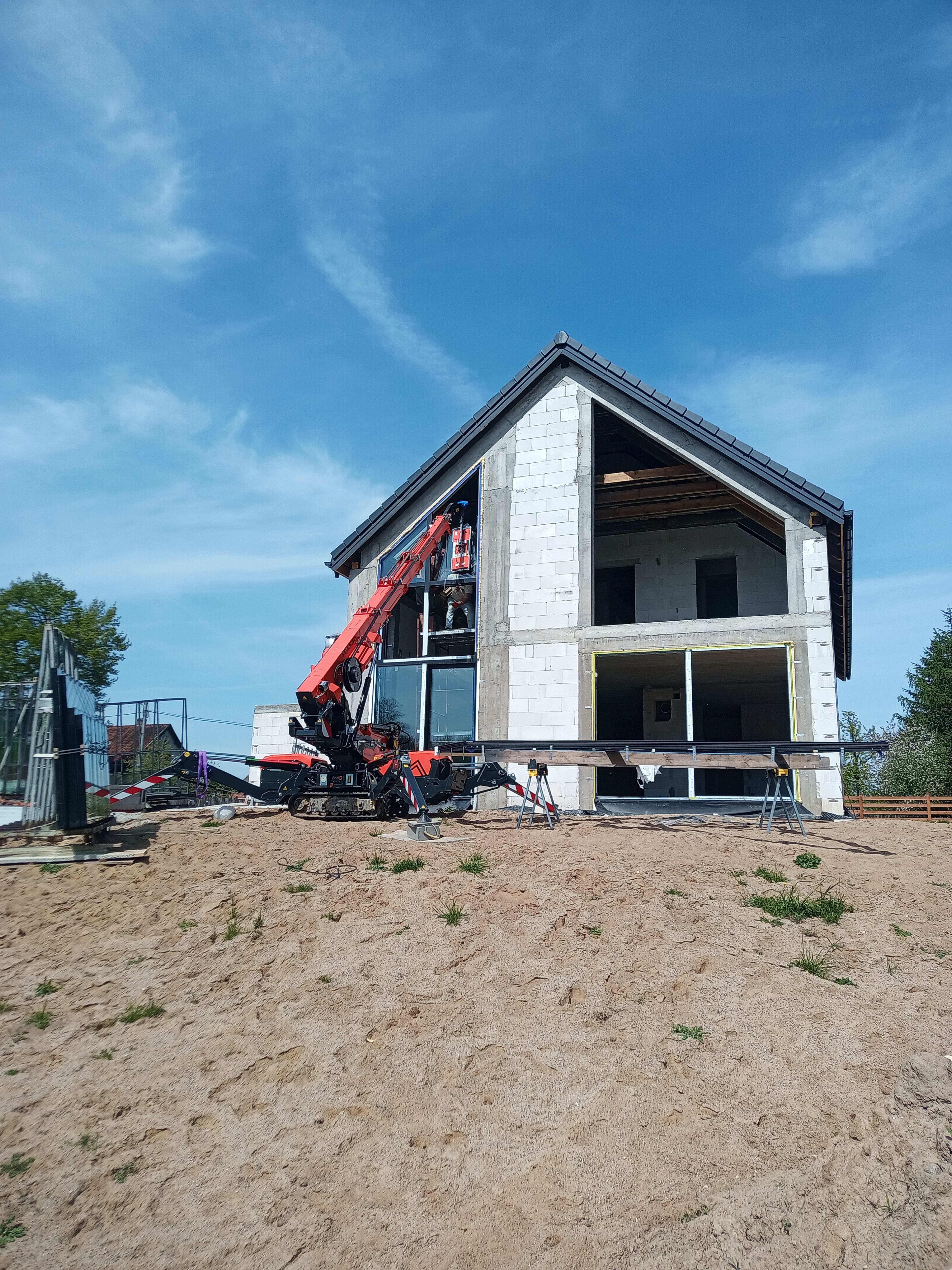 Aluminiowe: fasada dwukondygnacyjna, trójkątne okno panoramiczne oraz okno przesuwne typu HS w domu jednorodzinnym