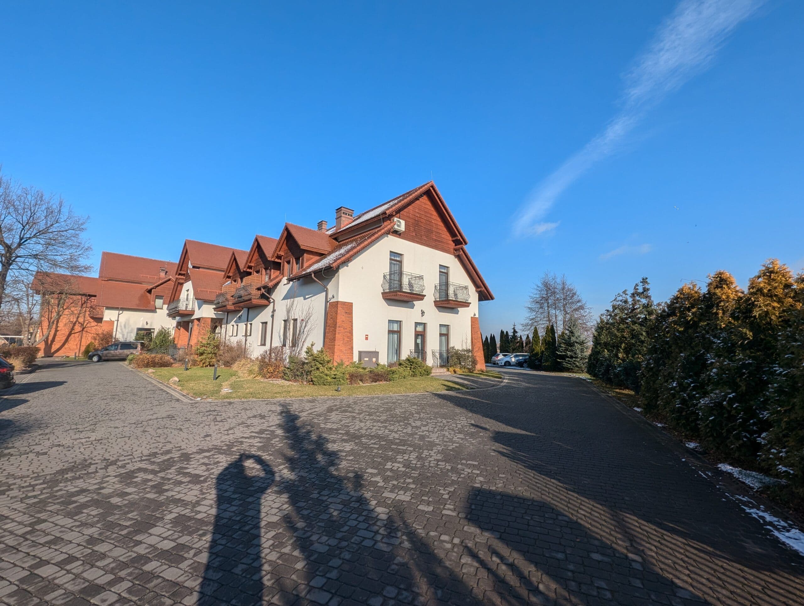 Okna aluminiowe w kolorze drewna oraz aluminiowe drzwi wejściowe z łukowymi doświetlami.