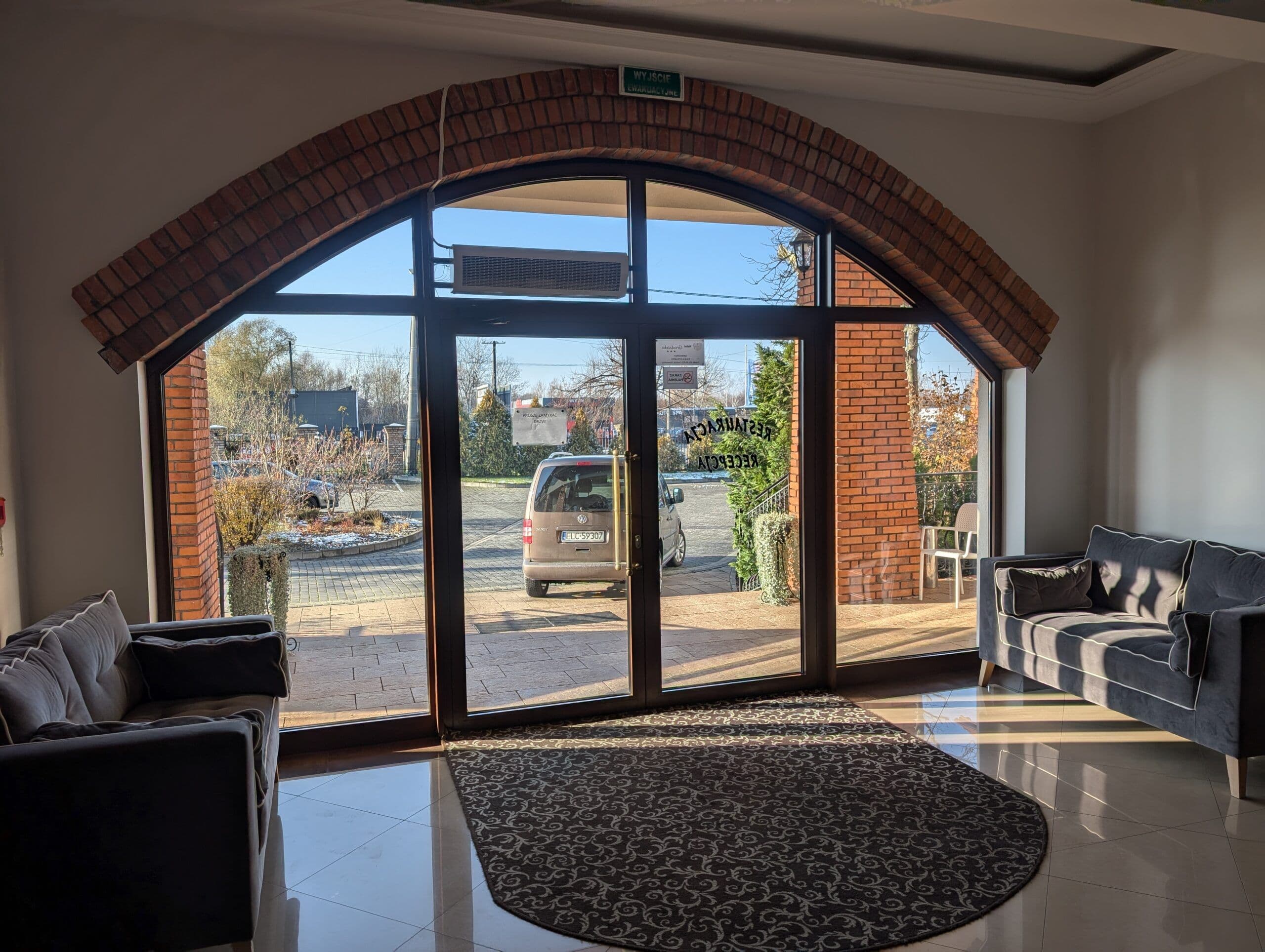 Okna aluminiowe w kolorze drewna oraz aluminiowe drzwi wejściowe z łukowymi doświetlami.