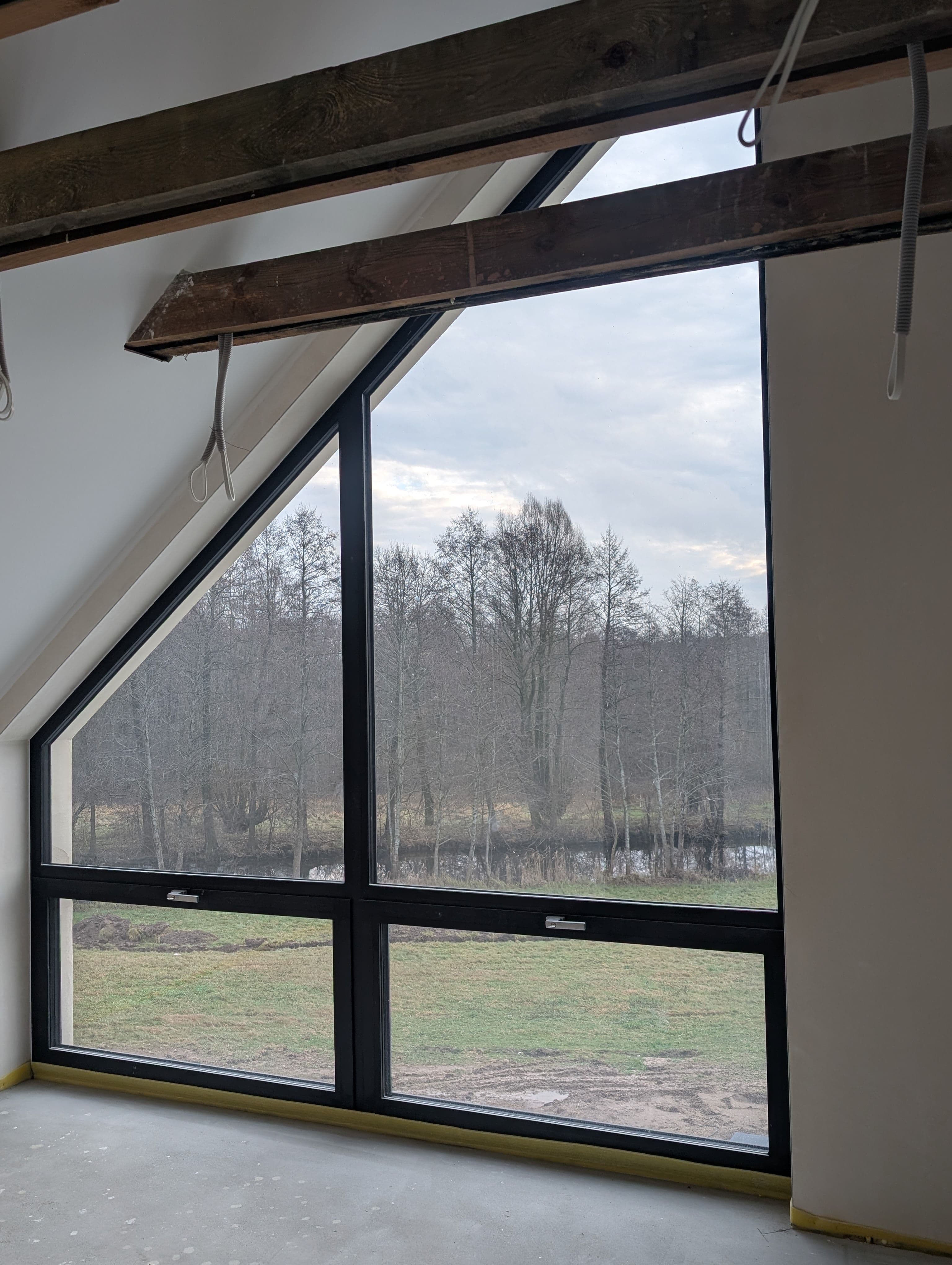 Aluminiowe: fasada dwukondygnacyjna, trójkątne okno panoramiczne oraz okno przesuwne typu HS w domu jednorodzinnym