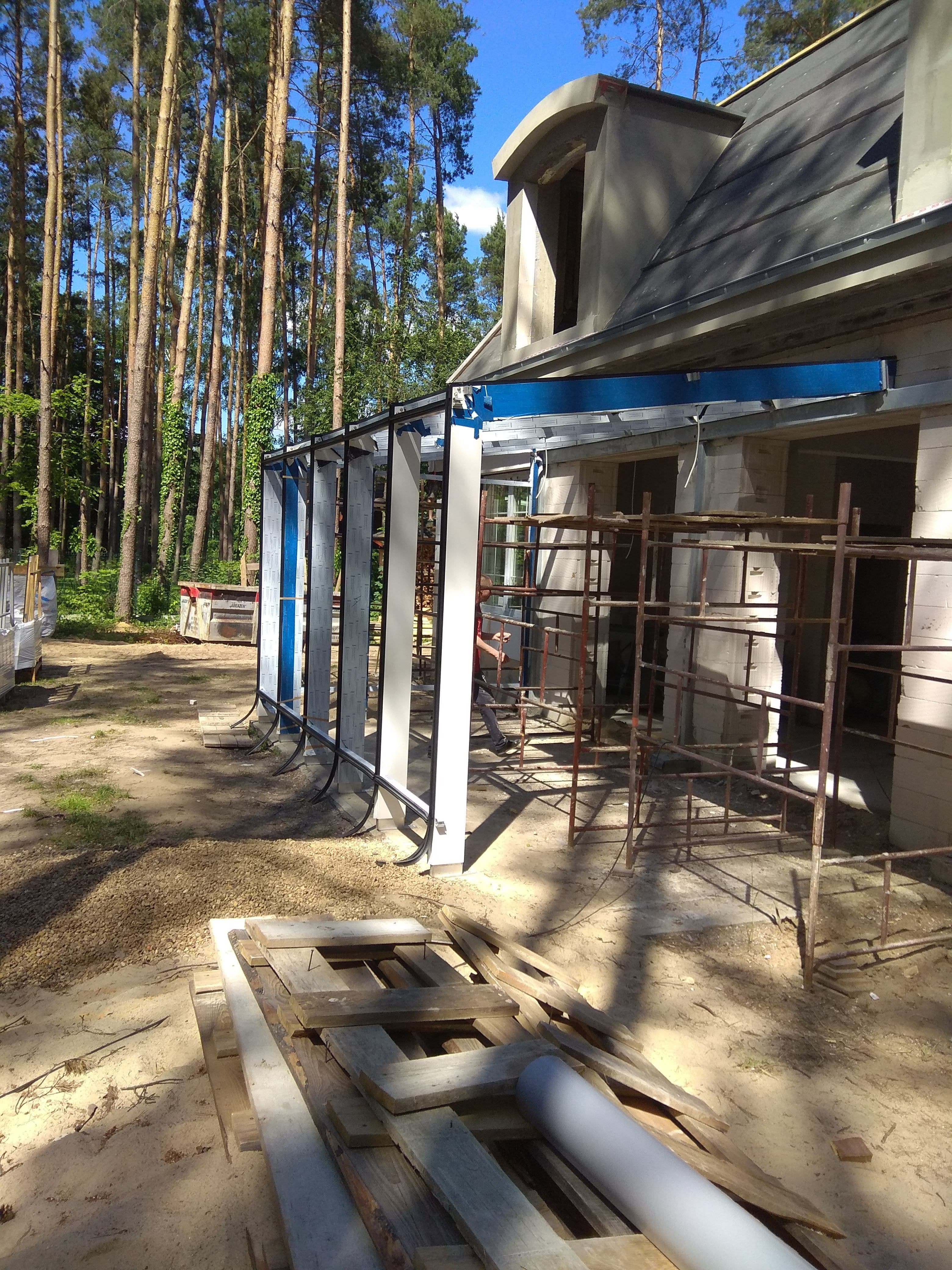 Ogród zimowy ze szklanym dachem na konstrukcji aluminiowej, białe okna aluminiowe z łukami i szprosami.