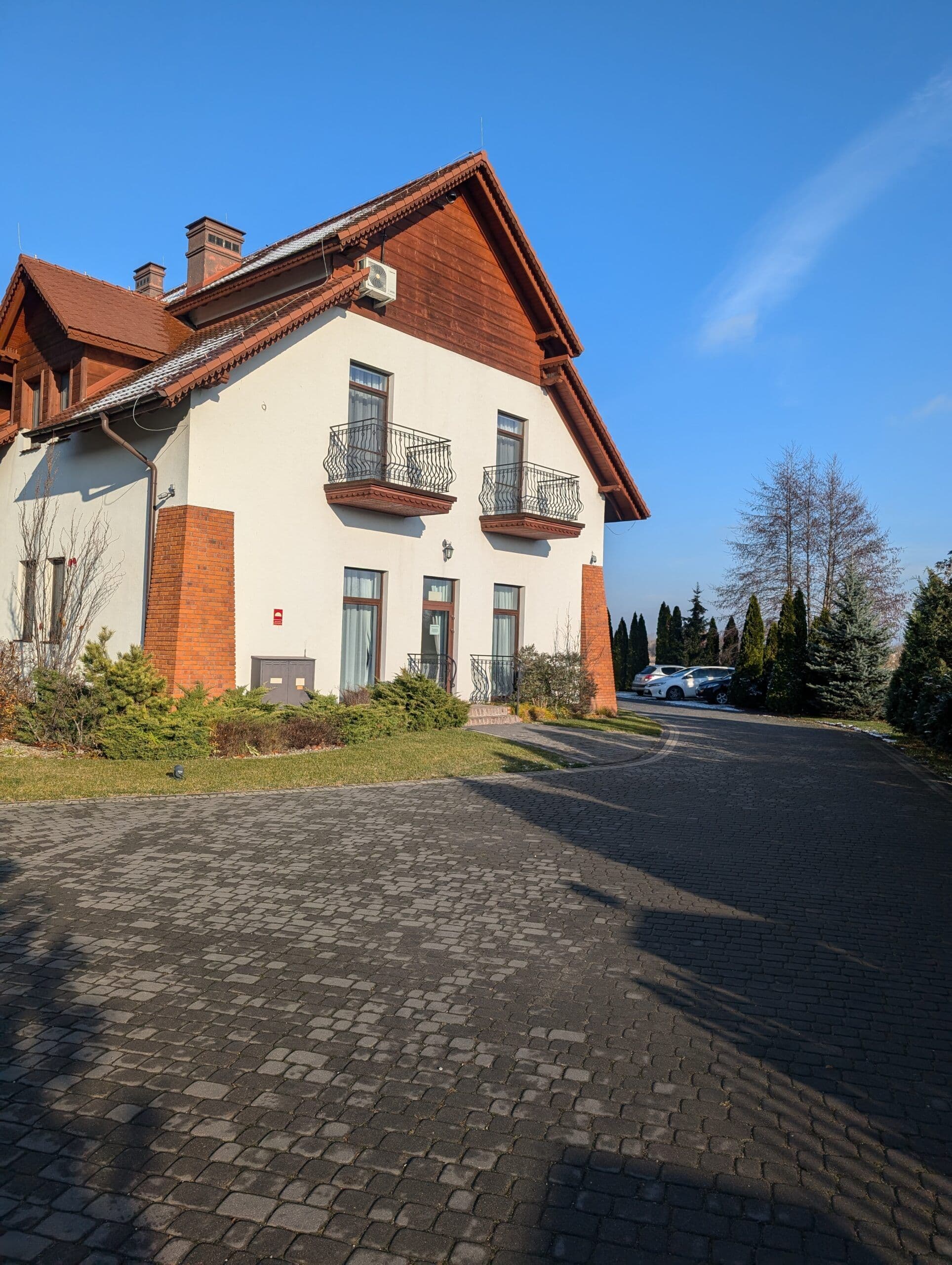 Okna aluminiowe w kolorze drewna oraz aluminiowe drzwi wejściowe z łukowymi doświetlami.